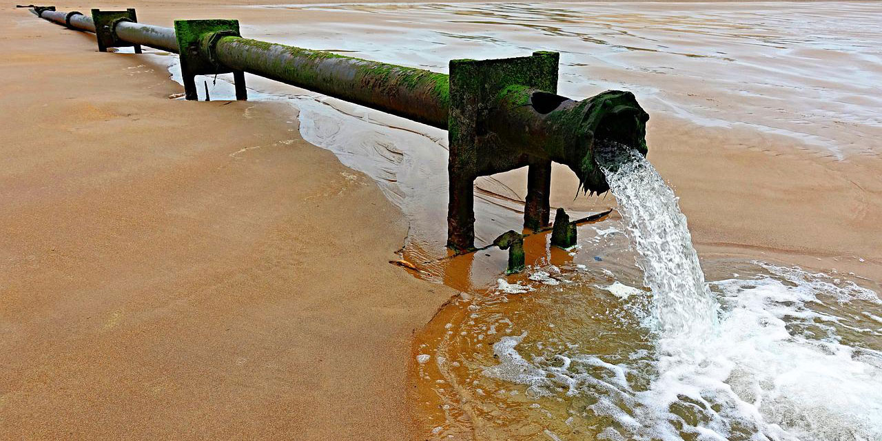 Abflussrohr entlädt Abwasser auf den Strand