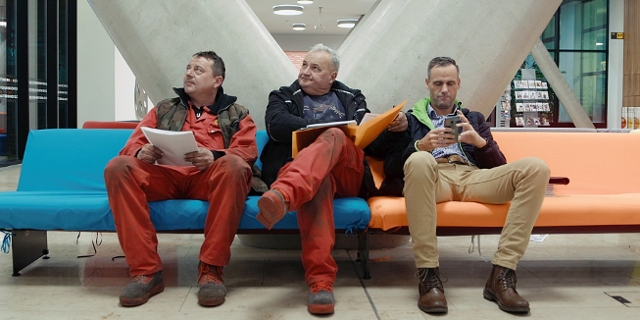 Drei Männer warten auf ihre Termine in der Arbeiterkammer Wien. Szene aus der Doku "Für die Vielen - Die Arbeiterkammer Wien" von Constantin Wulff.