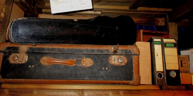 alter Koffer und diverse Mappen in einem Regal
