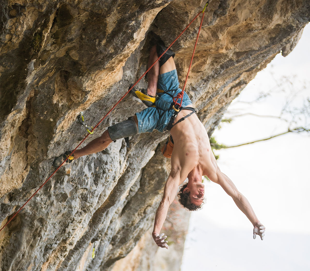 Kletterer Adam Ondra hängt kopfüber in einer Felswand und ruht sich aus