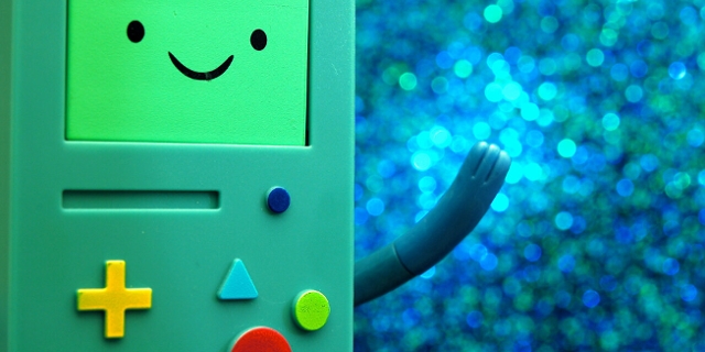 Ein Game Boy-artiges Spielzeug mit bunten Tasten und einem lachenden Gesicht.