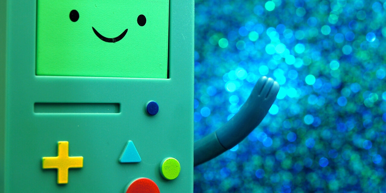 Ein Game Boy-artiges Spielzeug mit bunten Tasten und einem lachenden Gesicht.