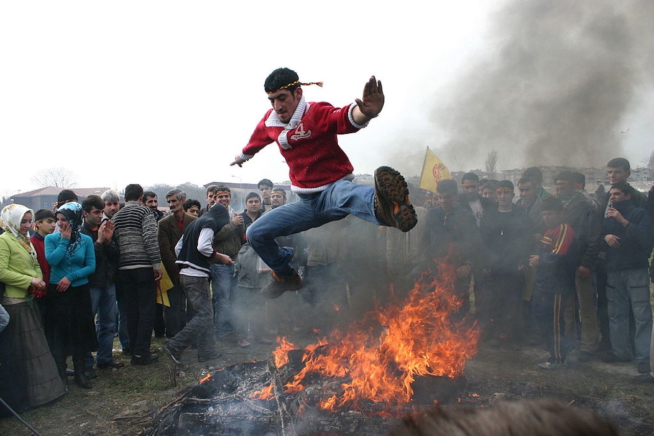 Newroz celebration in Istanbul - Mann springt über ein Lagerfeuer