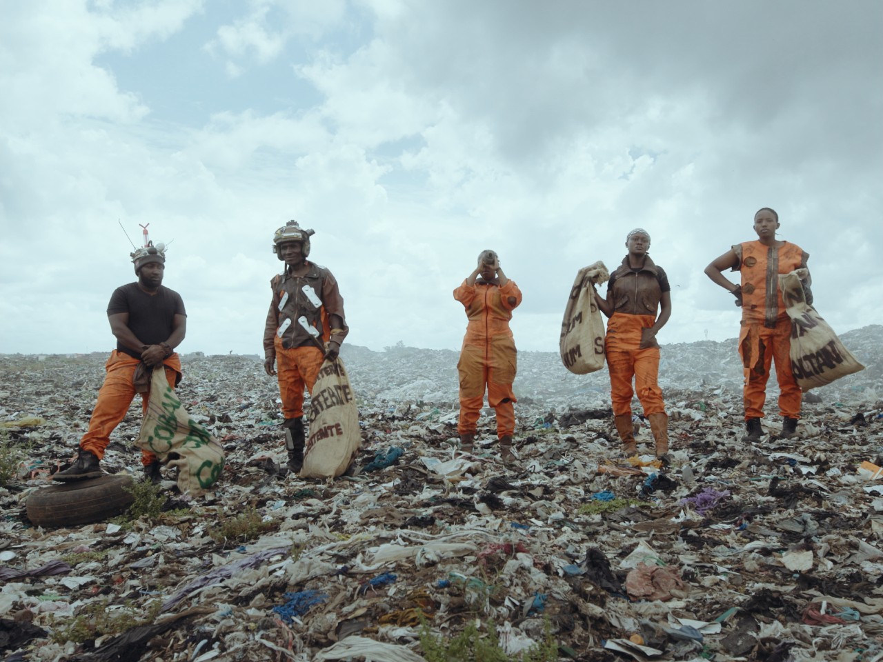 Fünf Menschen stehen auf Müllberg