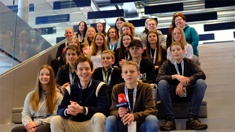 Ö3-Moderator Philipp Hansa sitzt mit Schülerinnen und Schülern der MS Windischgarsten auf der Ö3-Eventtreppe