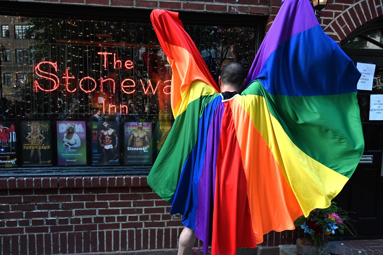 A man wears a rainbow cape as people gather for the 50th anniversary of the Stonewall Riots in front of the Stonewall Inn in New York, June 28, 2019