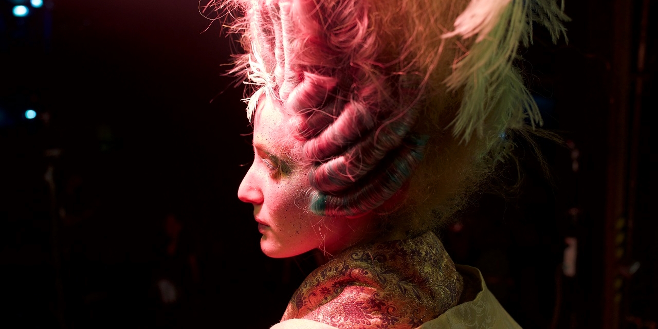 Haarmodel mit Drahtgestell für Dutt auf ihrem Kopf. Szene aus "Medusa Deluxe".