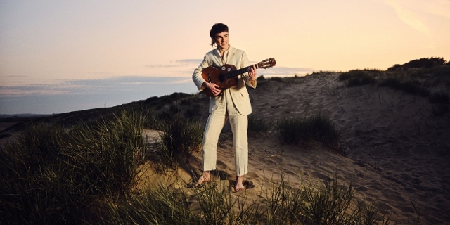 Declan McKenna steht mit Gitarre auf einem Hügel