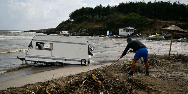 Aufräumen an bulgarischem Strand nach Überflutungen, kaputtes Wohnmobil steht im Sand