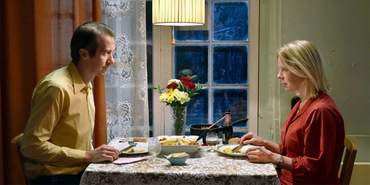 Szene aus "Fallende Blätter": Mann und Frau sitzen sich am Tisch gegenüber
