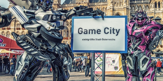 Zwei Transformers-Cosplayer mit einem Game City-Straßenschild.