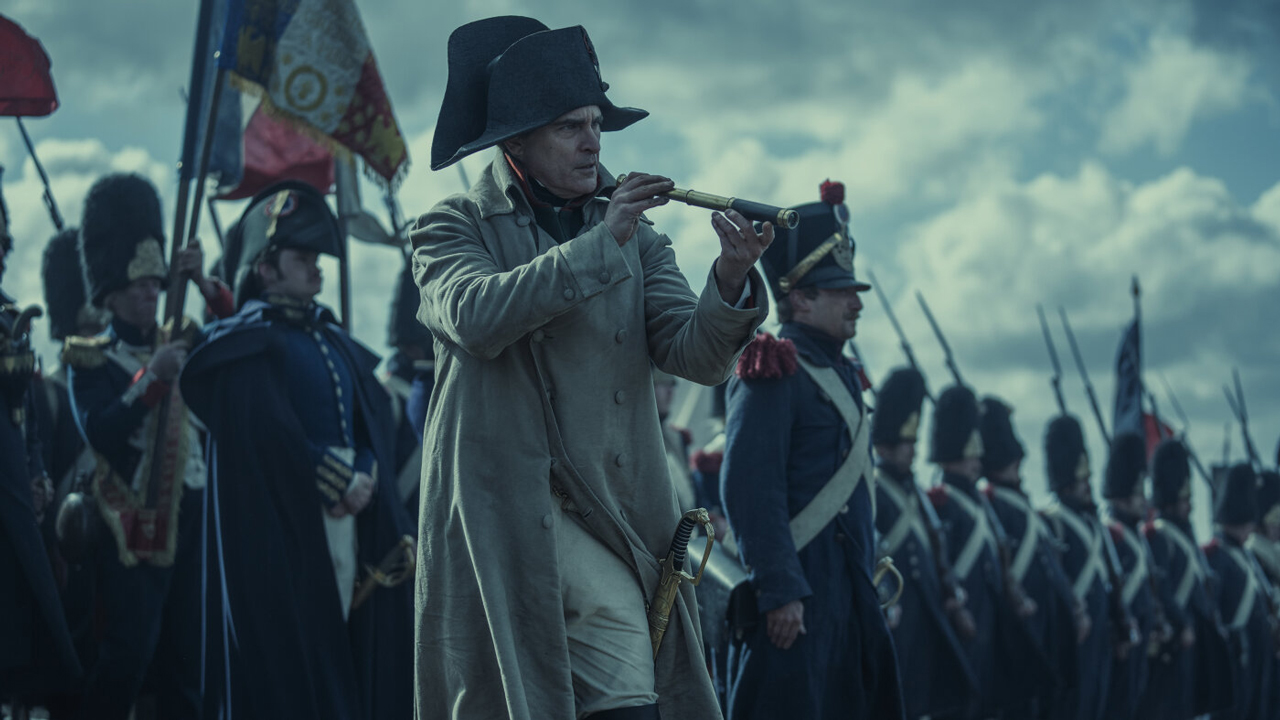 Joaquin Phoenix in "Napoleon" mit einem Fernrohr auf einem Schlachtfeld, hinter ihm Soldaten