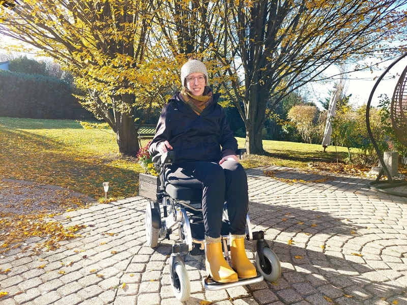 Astrid Hainzl im Freien im Rollstuhl sitzend