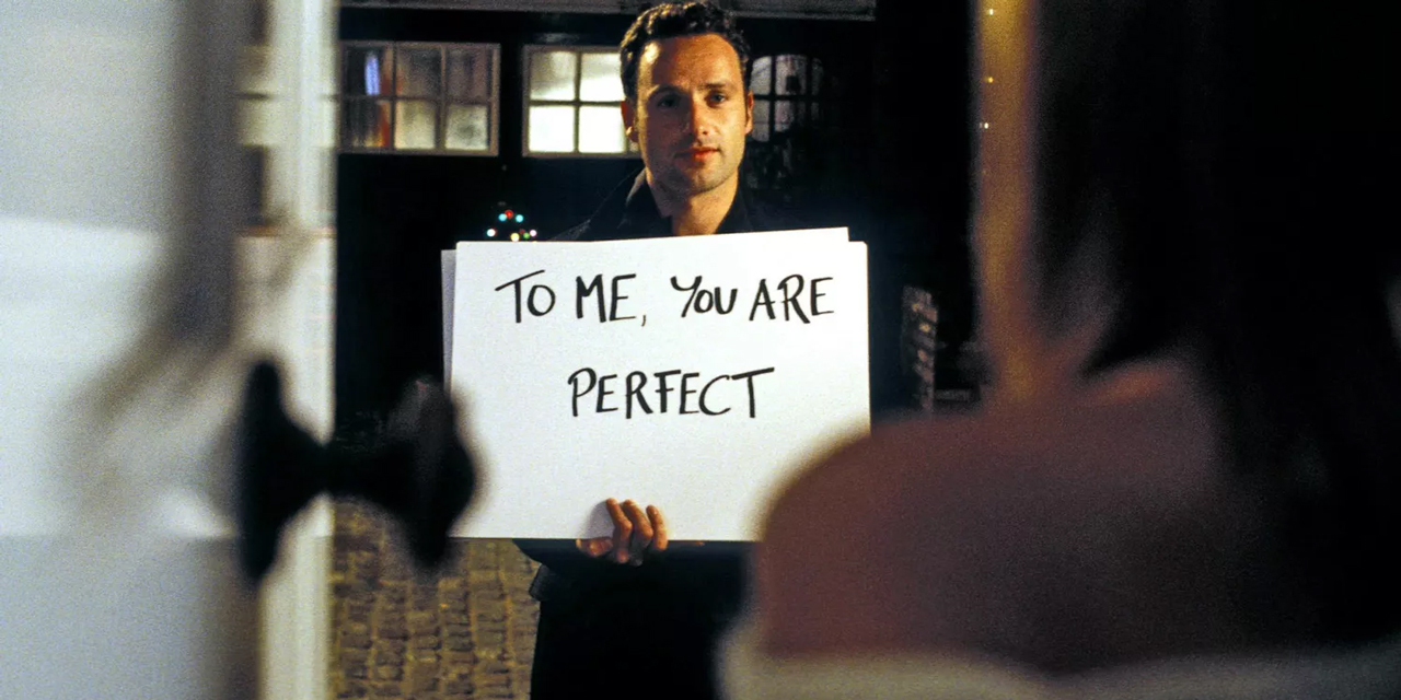 Ein Mann hält ein Schild mit der Aufschrift: "To me, you are perfect".