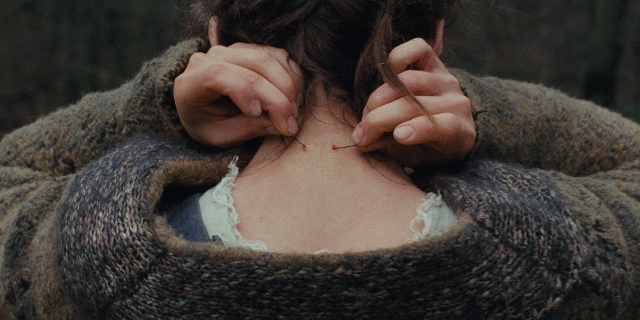 Szenenbild aus "Des Teufelsbad": Der Nacken einer Frau, sie zieht einen Faden durch die Haut