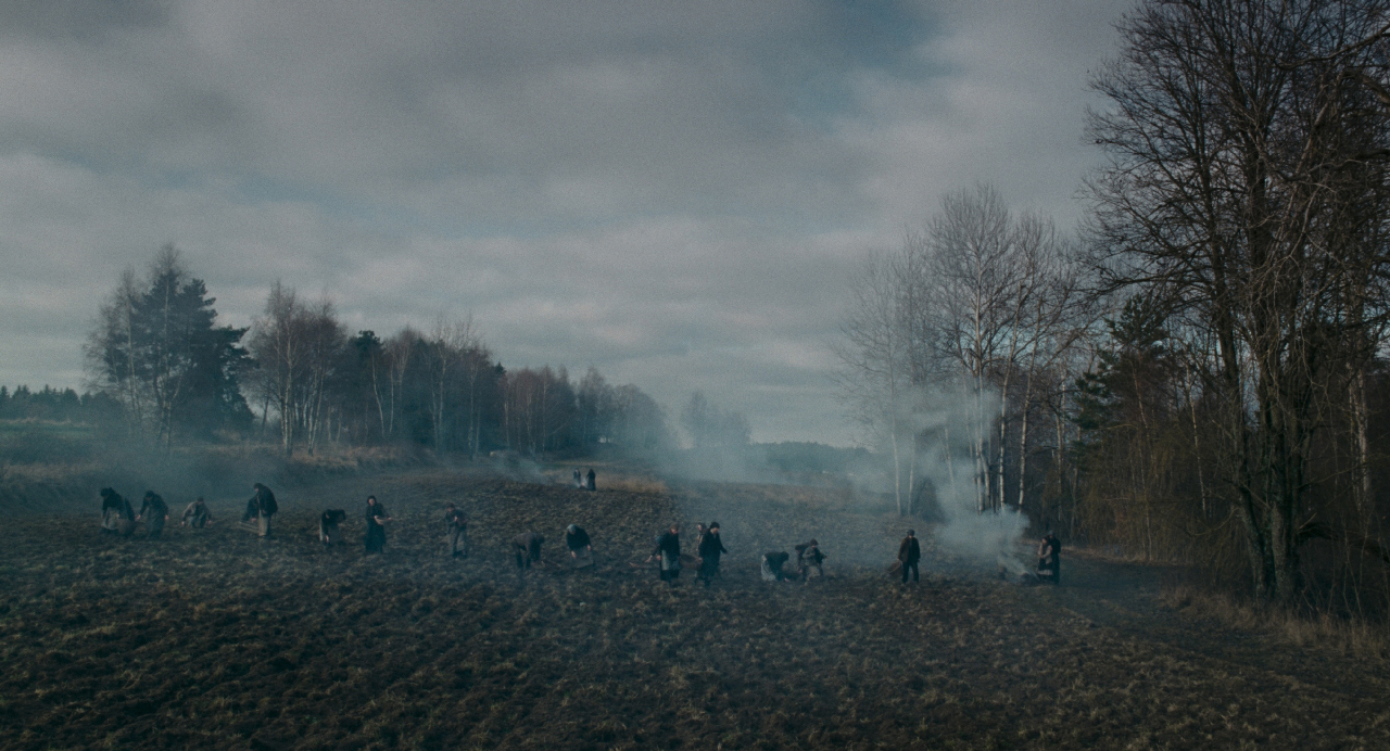 Szenenbild aus "Des Teufelsbad": Eine Reihe von Menschen auf einem herbstlichen Feld bei der Ernte von Erdäpfeln oder Ähnlichem