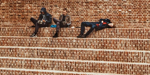 drei junge Männer sitzen auf ziegelroten Stufen