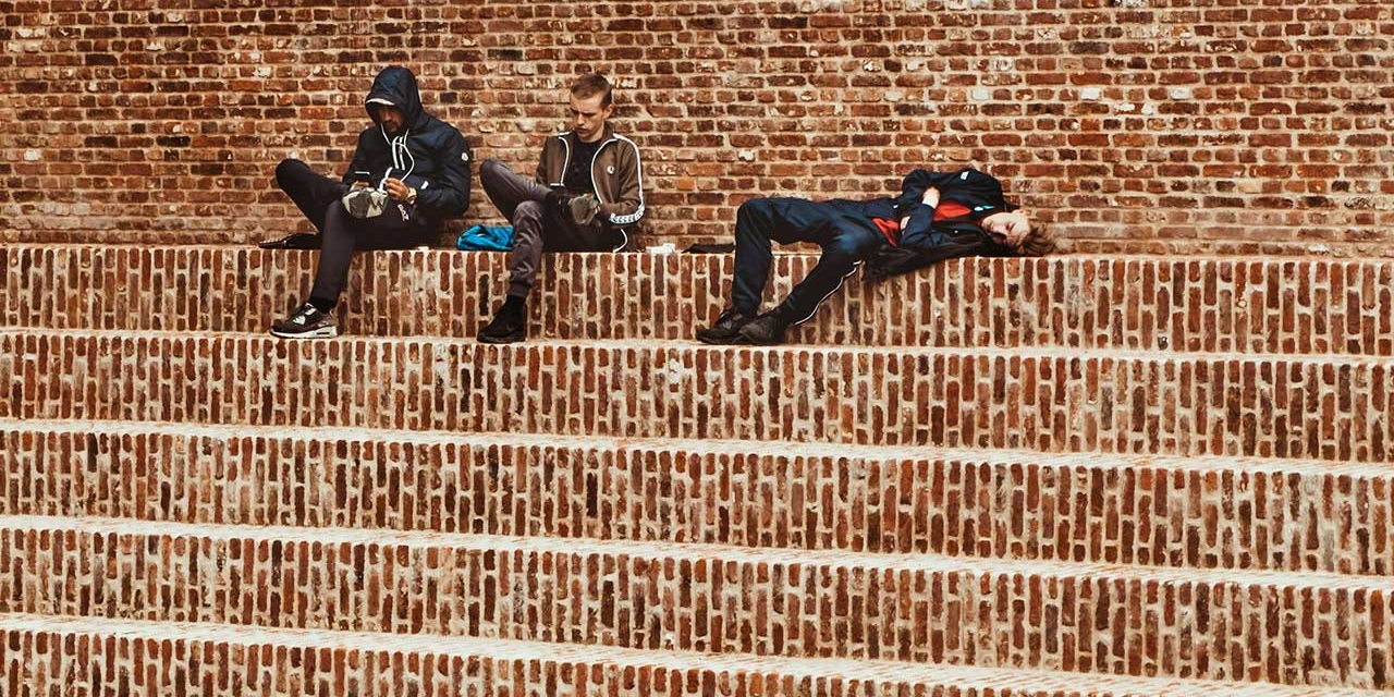 drei junge Männer sitzen auf ziegelroten Stufen