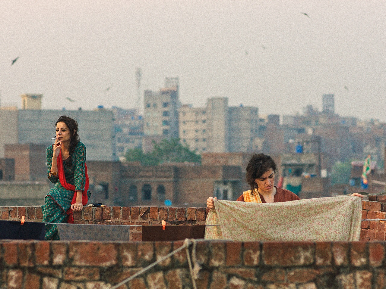 Zwei Ehefrauen beim Wäscheaufhängen auf einem Dach in einer Stadt in Pakistan. Szene aus dem Spielfilm "Joyland".