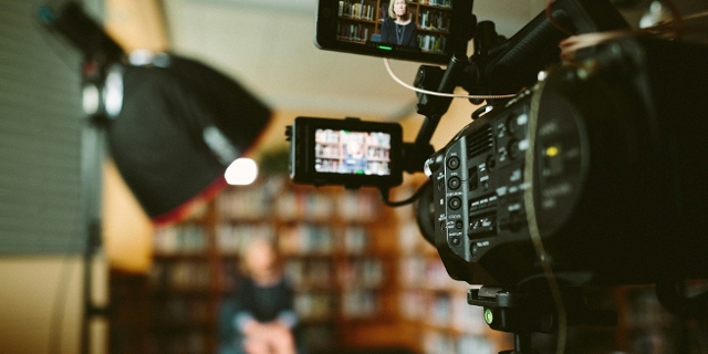 Filmkamera und unscharfes Filmset mit Frau vor Bücherwand