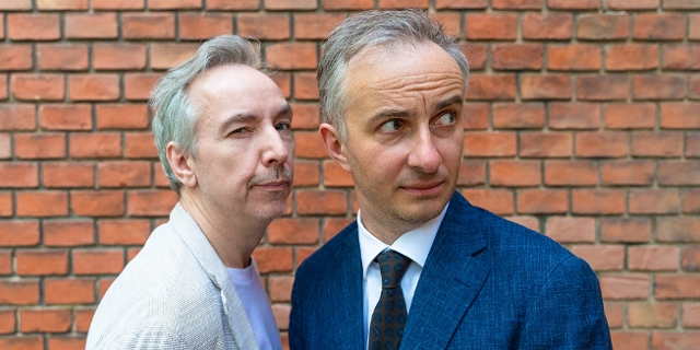 Olli Schulz und Jan Böhmermann vor einer roten Backsteinwand